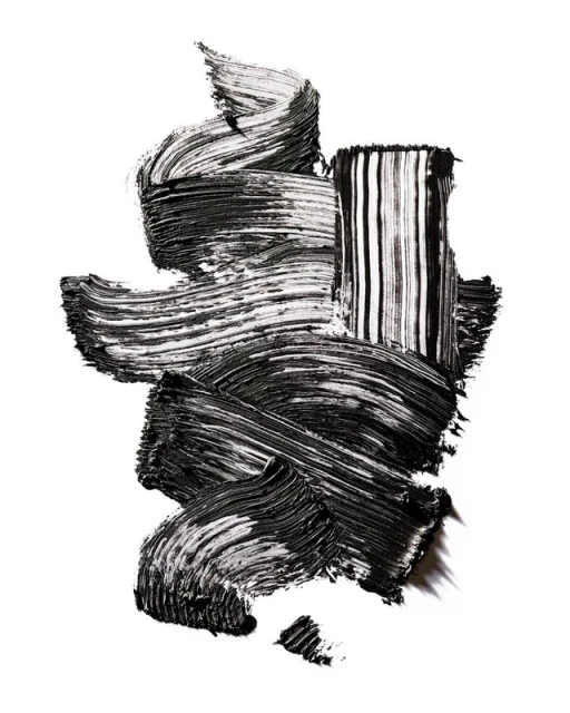 Abstract black smear of mascara brush strokes creating a textured pattern on a white backdrop, makeup concept for beauty ads.