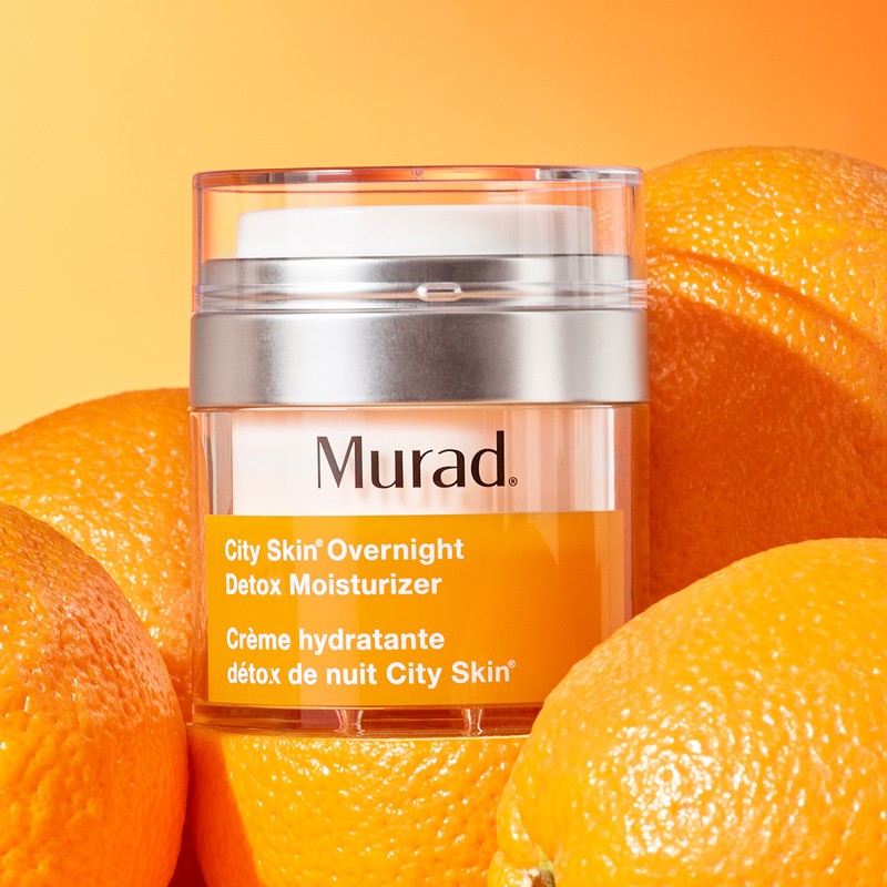 Murad City Skin Overnight Detox Moisturizer jar with oranges in a brightly lit studio setting, product and beauty advertising.