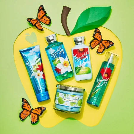 Bath & Body Works 'Beautiful Day' collection displayed with butterfly decorations on a light green background, product photography.