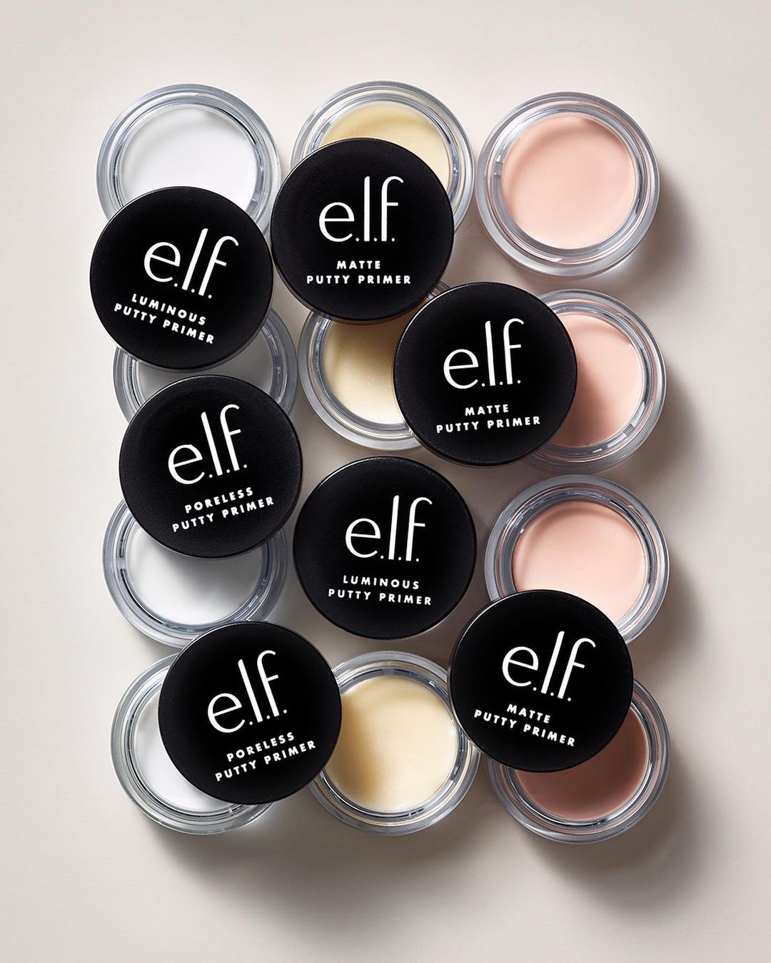 Close-up of assorted e.l.f. putty primers in their containers, including matte, luminous, and poreless varieties, on a neutral surface.