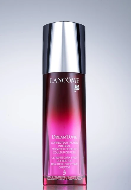 Lancôme DreamTone dark spot corrector bottle on a grey background. Beauty and personal care product shot in studio with studio lighting.