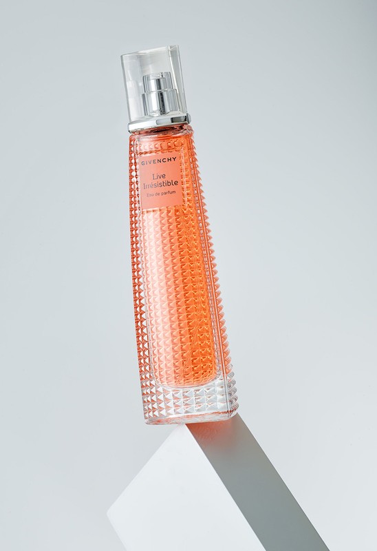 Givenchy 'Live Irresistible' perfume bottle sits on a white surface against a grey background in a studio product shot.