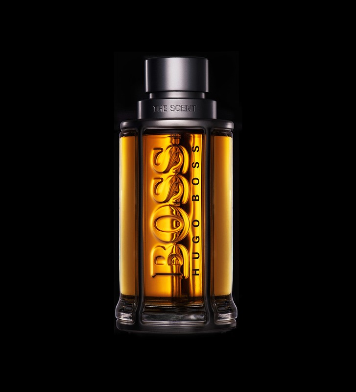 Studio shot of a Hugo Boss cologne bottle on a black background, showcasing the amber liquid and bold branding in vertical composition.