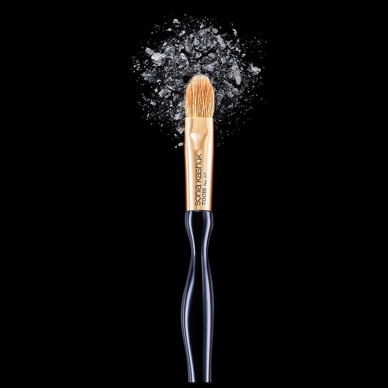 Cosmetic brush on black background surrounded by silver eye shadow powder. Beauty shot for beauty supply store or cosmetic company.