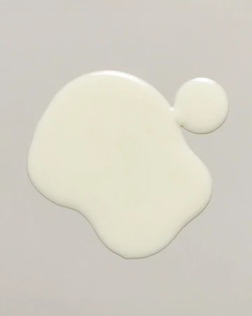 Overhead shot of a blob of spilled white fluid on a gray surface. The white fluid has an organic, irregular shape.