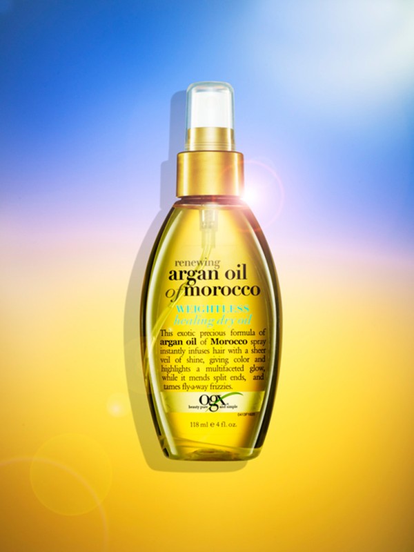 Renewing argan oil of morocco weightless spray bottle. Clear bottle with gold accents on a blue and gold gradient background.