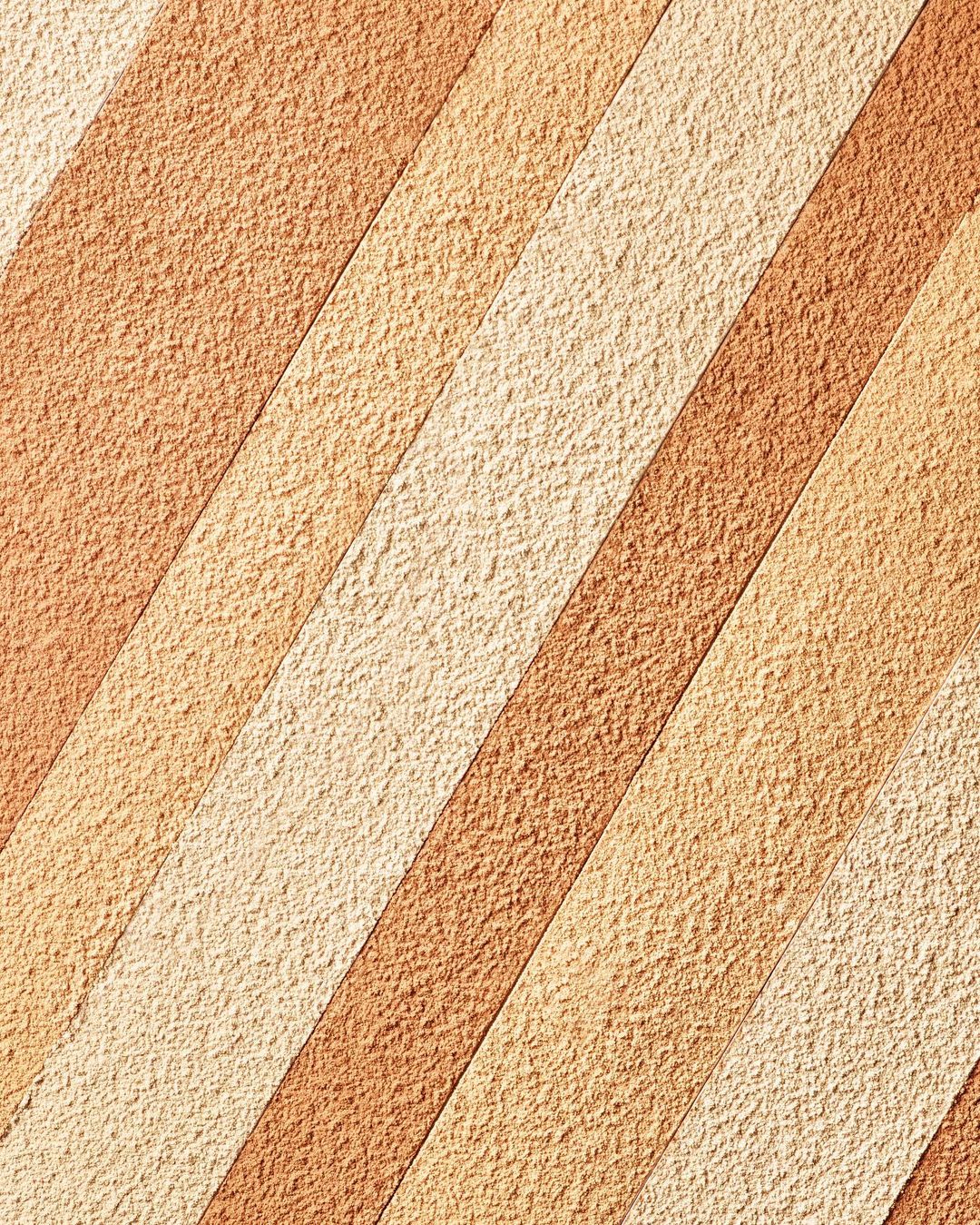 Abstract textured background with alternating diagonal stripes in shades of beige and brown, creating a visually appealing pattern.