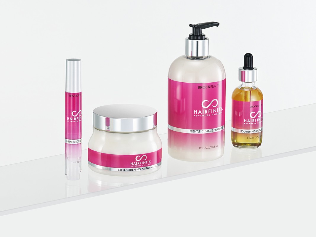 Hairfinity haircare product line on a white surface includes shampoo, oil, mask, and serum, featuring pink labels with the Hairfinity logo.