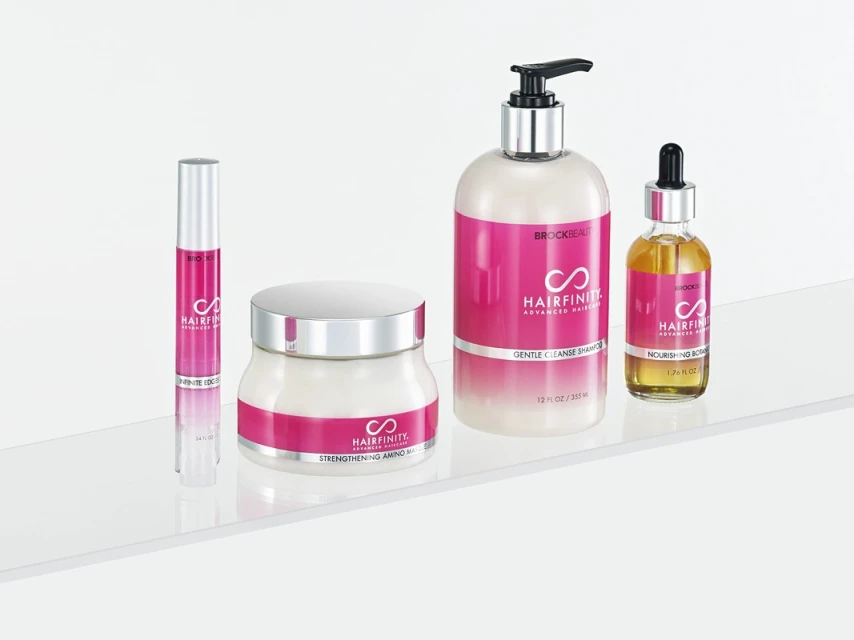 Hairfinity haircare product line on a white surface includes shampoo, oil, mask, and serum, featuring pink labels with the Hairfinity logo.