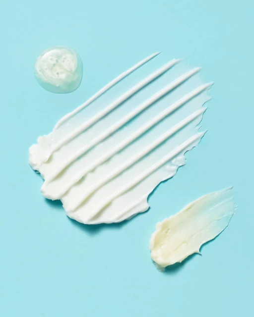 Close-up shot of white and clear skincare product smears against a light blue backdrop. Ideal for beauty and cosmetic promotions.
