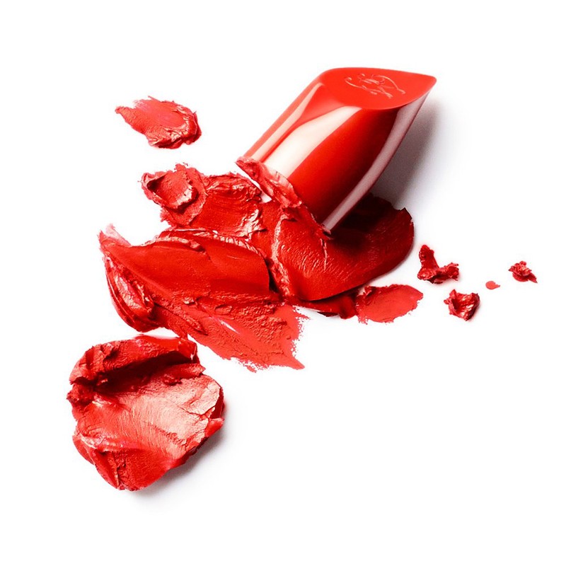 Close-up of broken red lipstick pieces, featuring vibrant color and textures, against a clean white backdrop, perfect for beauty concepts.