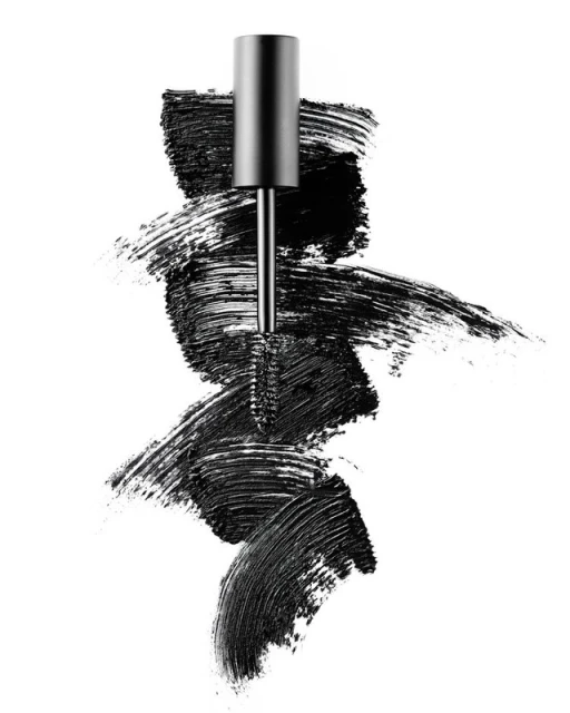 Mascara wand with black mascara smears on a white background, eye makeup product shot for beauty and cosmetics advertising.