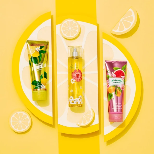 Three cosmetic product tubes and a spray bottle arranged with lemon slices on a bright yellow background in a studio shot.