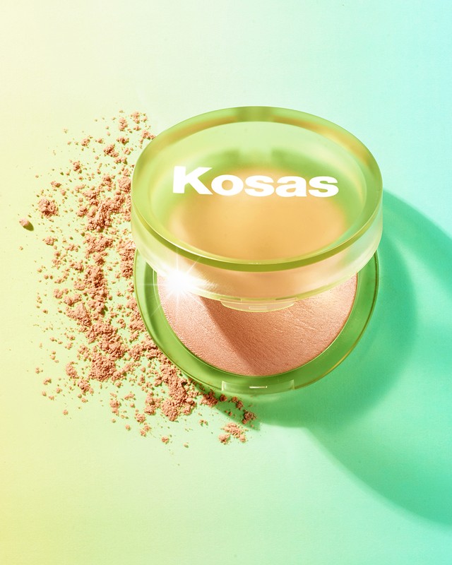 Kosas Revealer Skin-Improving Powder Foundation product shot. Makeup powder near compact, light green and yellow background.