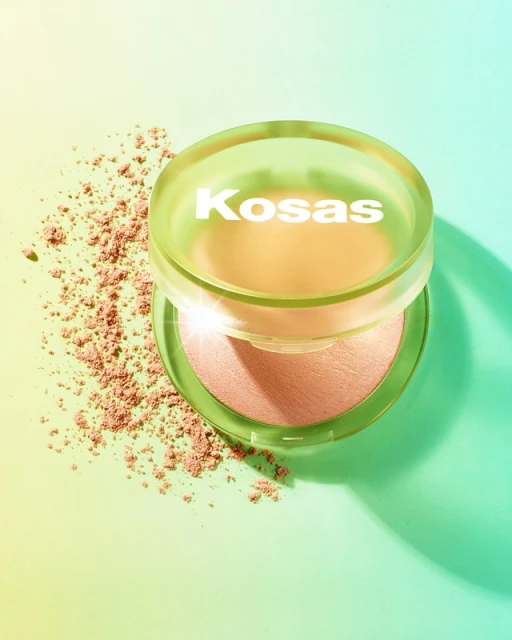 Kosas Revealer Skin-Improving Powder Foundation product shot. Makeup powder near compact, light green and yellow background.
