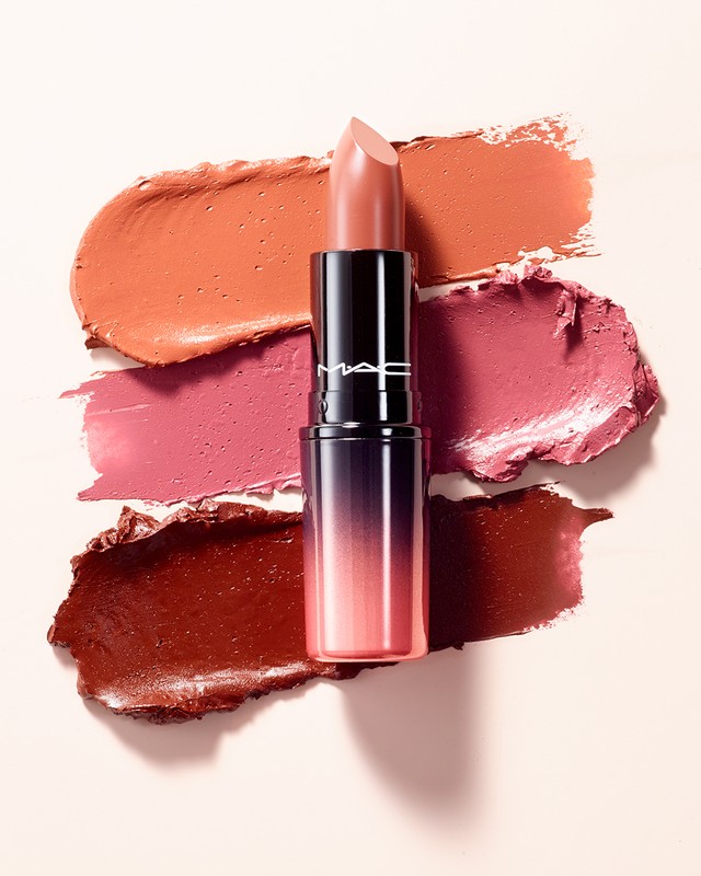 Close-up of a lipstick tube with several shades of lipstick swatches on a pale background, cosmetics, and beauty product photography.
