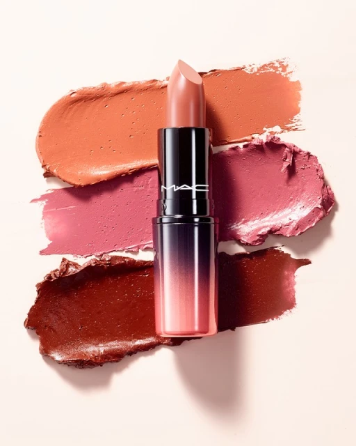 Close-up of a lipstick tube with several shades of lipstick swatches on a pale background, cosmetics, and beauty product photography.