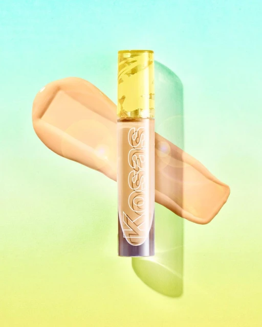 Kosas Revealer Concealer with swatch on a light teal and yellow background, beauty and cosmetics product photography.