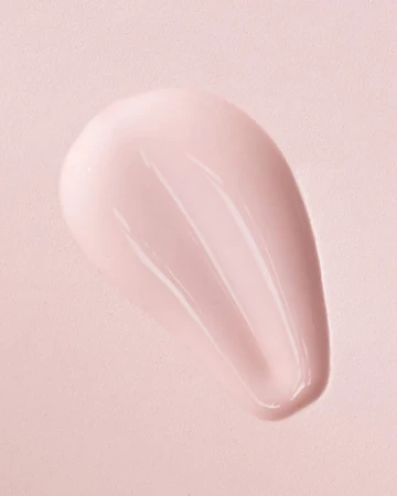 Close-up of a pink cosmetic cream swatch smeared on a matching pink textured background surface.
