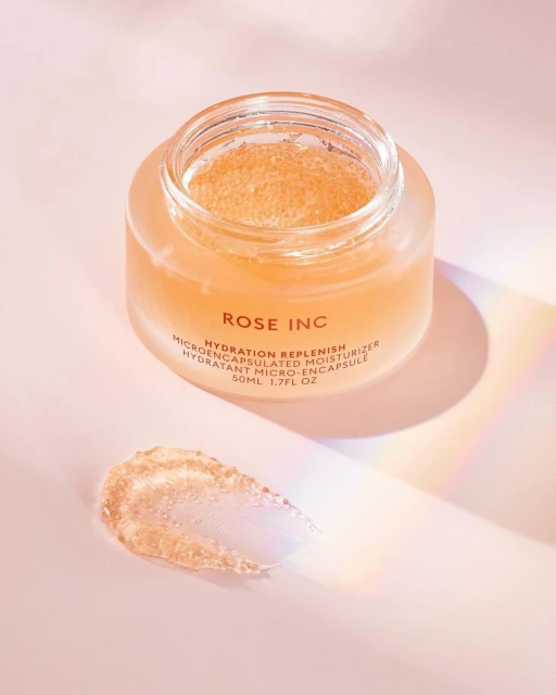 Rose Inc Hydration Replenish moisturizer in a glass jar with product swatch on a pink surface with light and shadow effects.