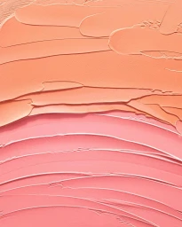 Close-up macro shot of textured peach and pink cosmetic cream swatches with visible ridges and smooth strokes.