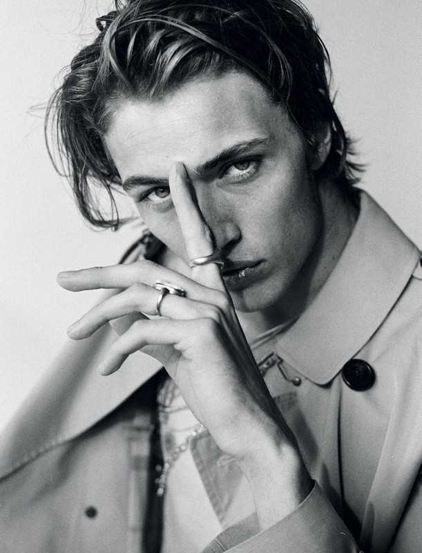 Close up monochrome portrait of a young man with rings on his fingers wearing a light coat styled by Marc Anthony George