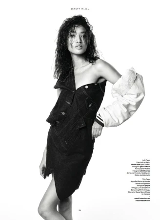 Black-and-white fashion portrait of a young adult Asian woman wearing a deconstructed denim dress and varsity jacket sleeve in a studio.