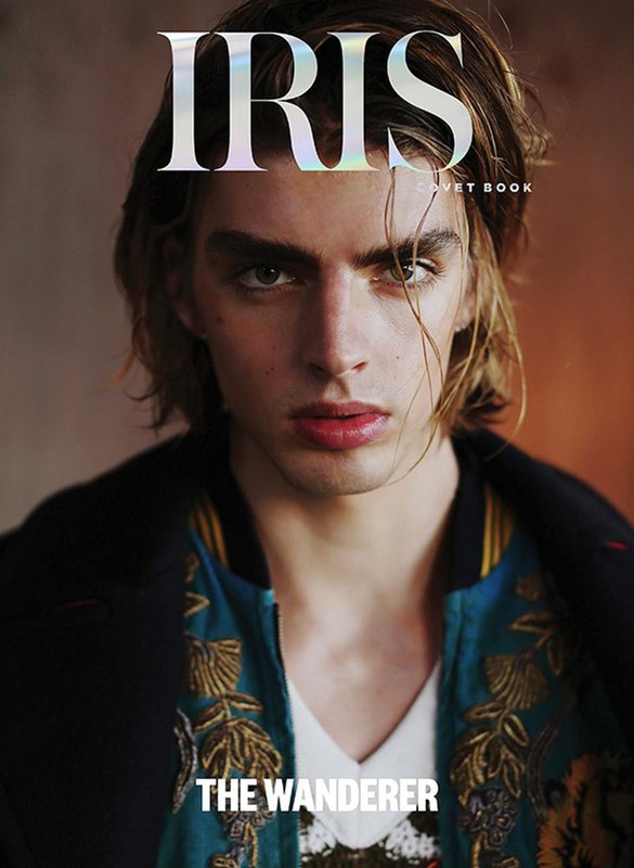 Magazine cover shot of a fair-skinned male model with long blonde hair, wearing a white v-neck shirt and embroidered jacket.