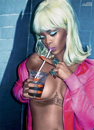 Close-up portrait of a young adult female with blonde hair drinking from a plastic cup, wearing a pink top and rings, against a blue wall.