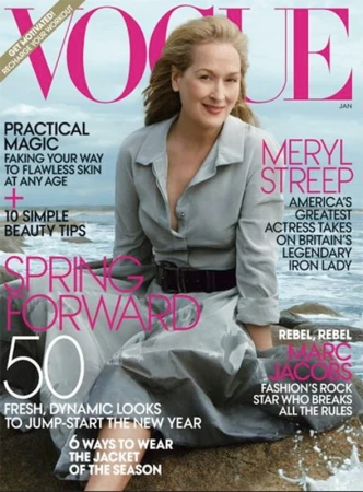 Vogue magazine cover featuring Meryl Streep in a gray dress, sitting on a rock at the beach, with bold pink typography.