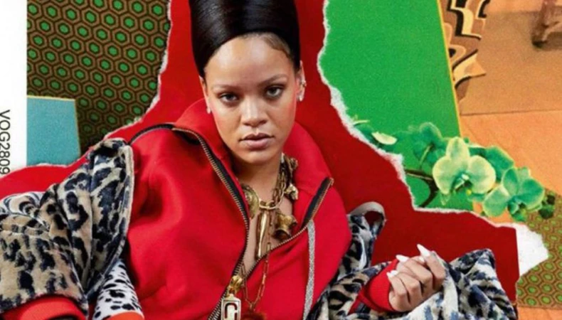 Rihanna wearing a red zip hoodie and leopard print coat with elaborate sculpted updo hair and long white nails.