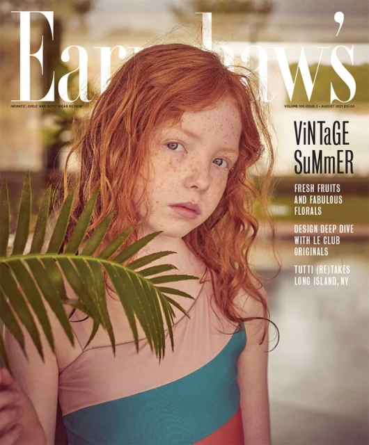 Magazine cover featuring a young red-haired girl in a color-blocked swimsuit, with a palm frond in the foreground and summer themes.