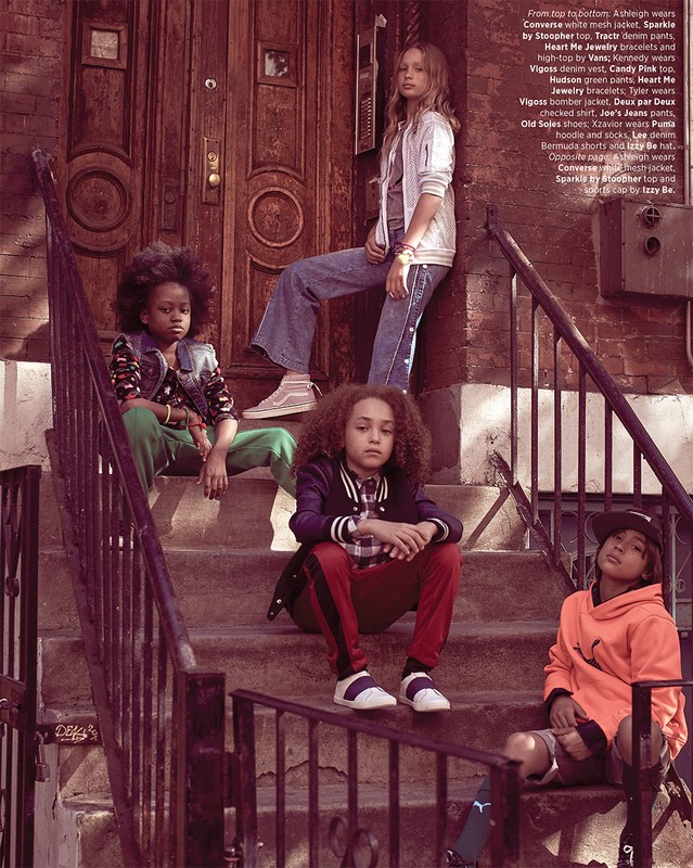 Four children are seated on outdoor stairs, showcasing casual fashion against an urban backdrop, styled in denim, sporty jackets, and jeans.