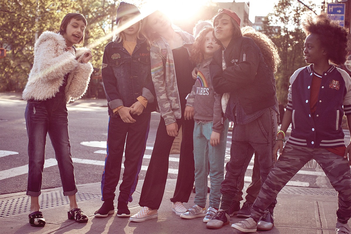 Group of stylish children standing together on city street. Diverse group of children's fashion with trendy jackets, pants, and sneakers.