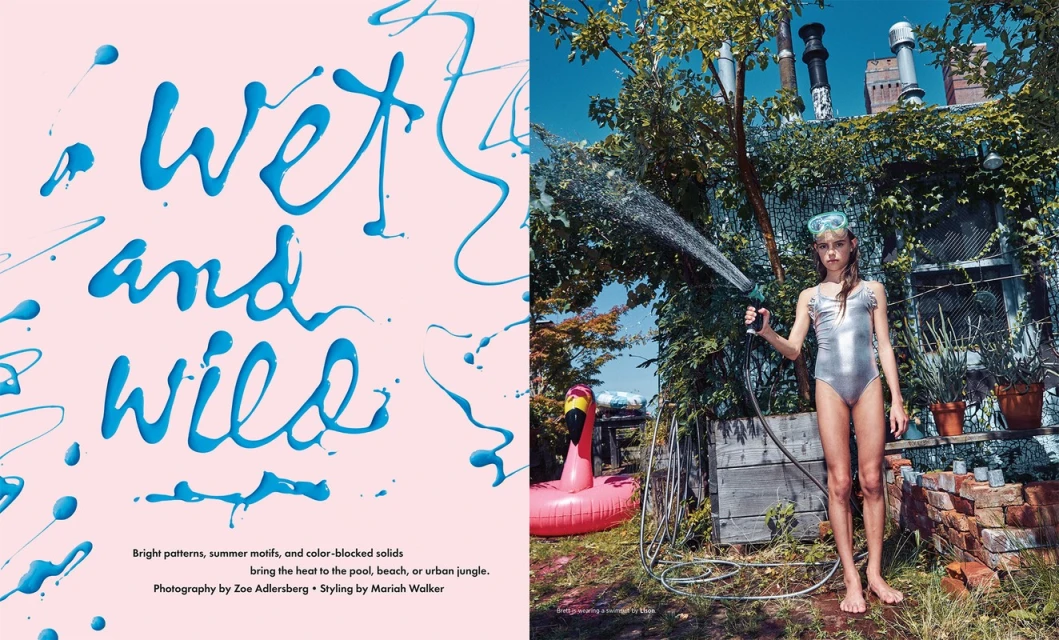 Young girl in swimsuit outside spraying a hose. Text overlay reads 'wet and wild'. Pink flamingo floatie and foliage in the yard.