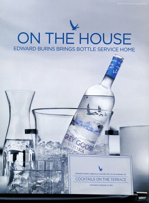 Grey Goose vodka bottle displayed in an ice-filled bucket, with clear glasses and a drink invitation card in a cool, inviting setting.