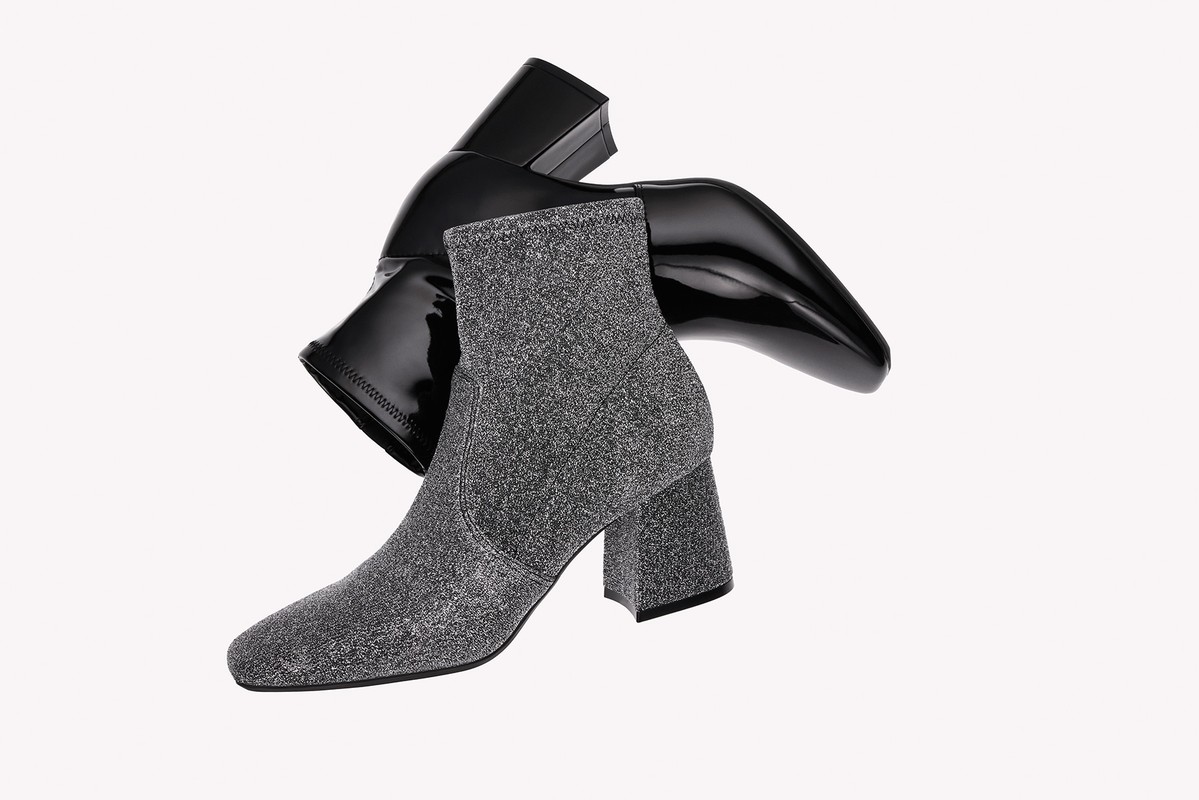 Two fashion ankle boots: one in grey textured fabric and one in shiny black patent leather on an isolated white background.