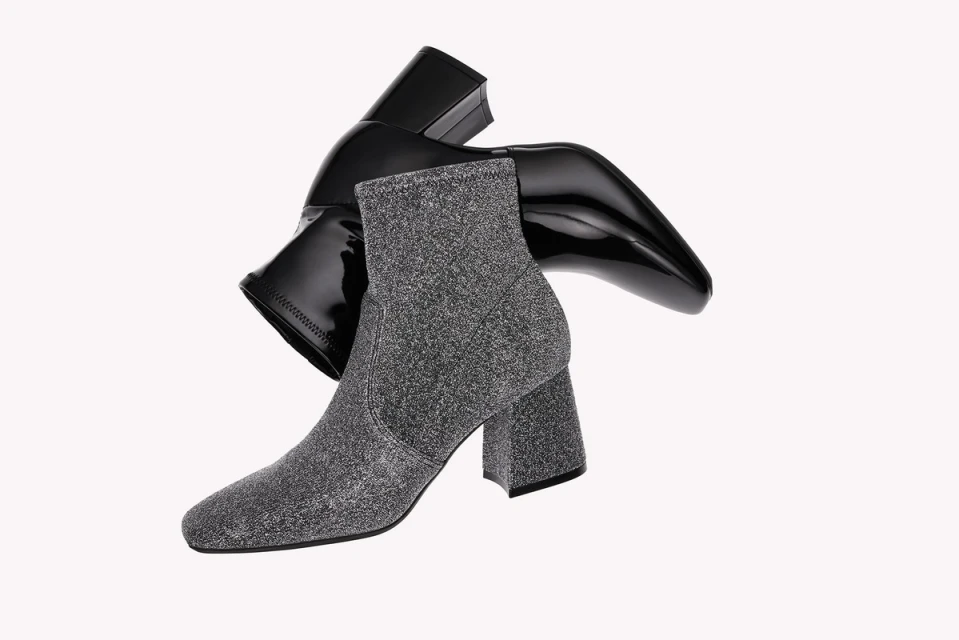 Two fashion ankle boots: one in grey textured fabric and one in shiny black patent leather on an isolated white background.