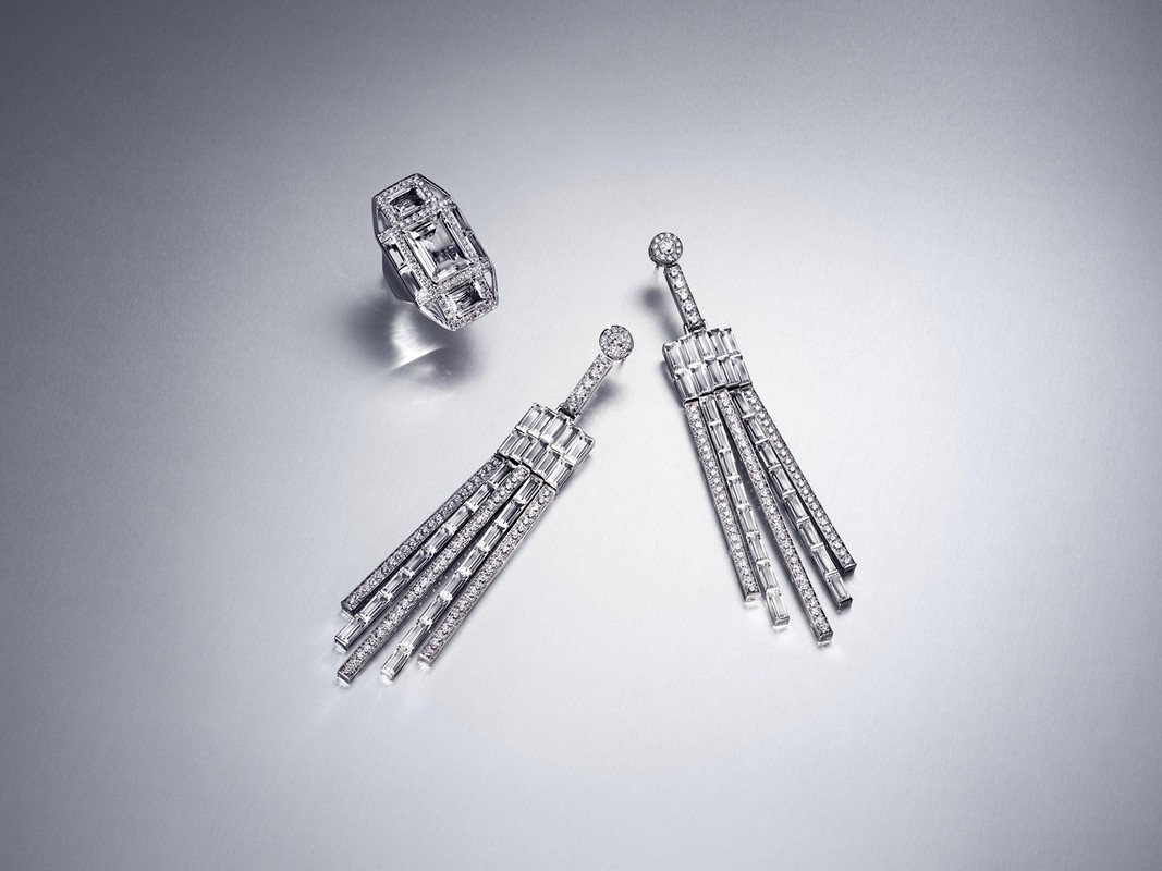 Diamond earrings and a ring are arranged against a silver background, showcasing the jewelry's sparkle and design.
