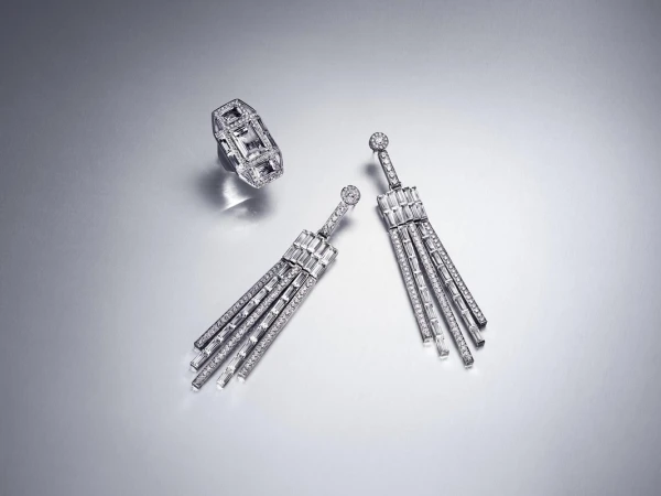 Diamond earrings and a ring are arranged against a silver background, showcasing the jewelry's sparkle and design.