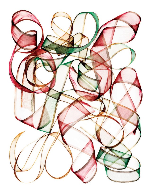 Abstract close-up of translucent red, green, and gold ribbons intertwined and floating against a bright white background.