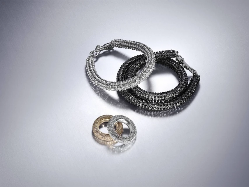 Silver and gold bracelets featuring a sparkly design against a shiny silver background, captured in a studio setting.