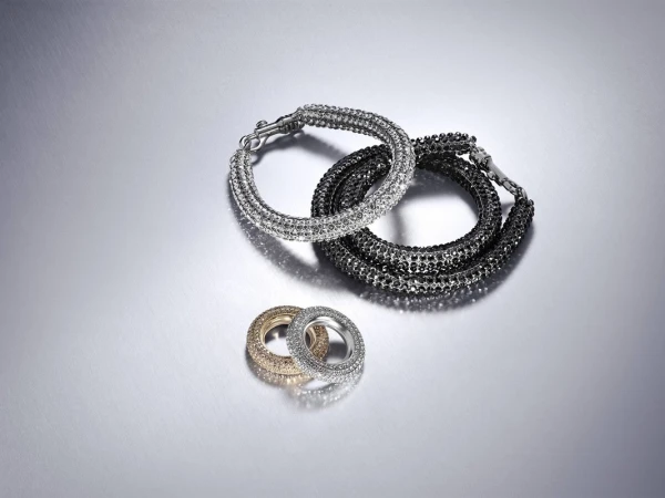 Silver and gold bracelets featuring a sparkly design against a shiny silver background, captured in a studio setting.