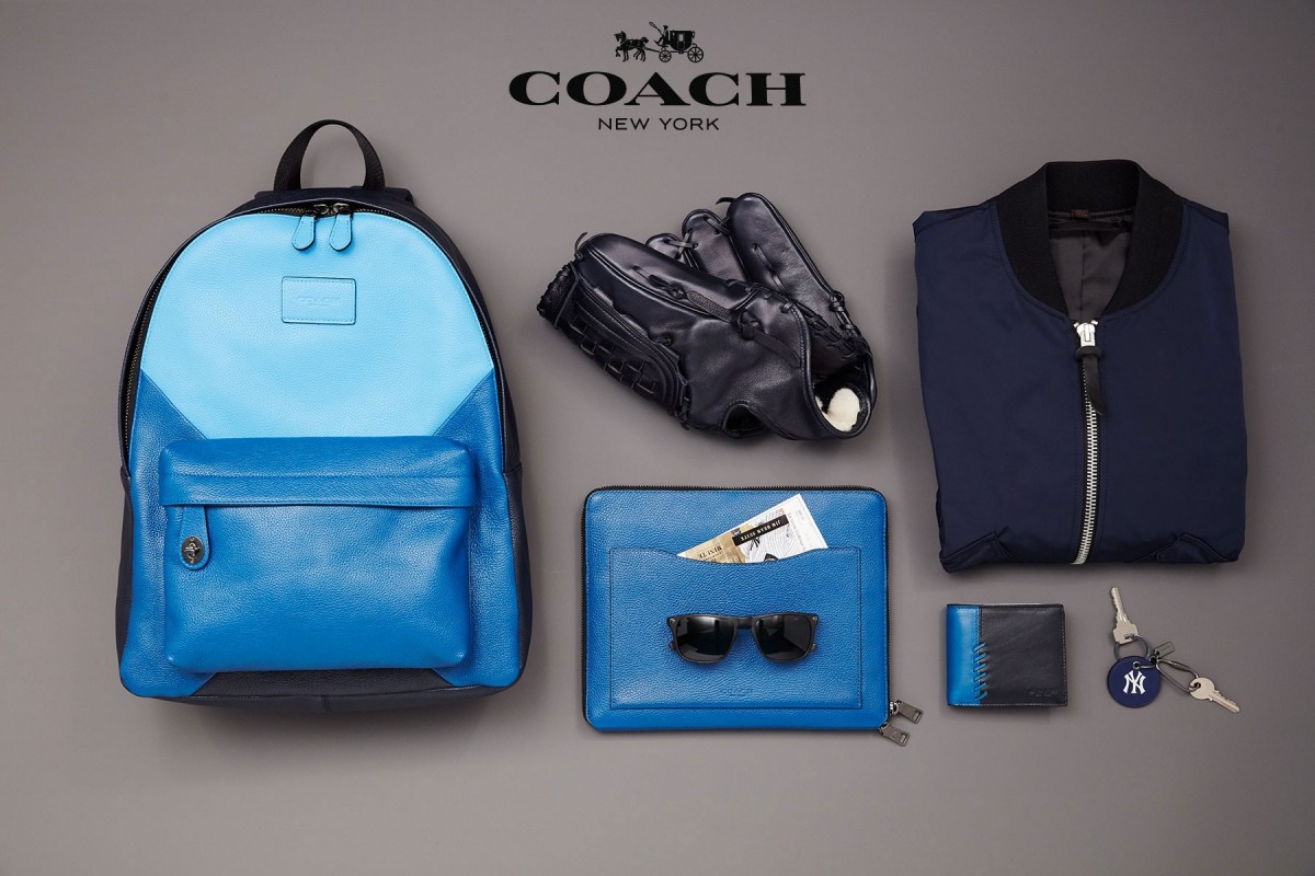 Coach brand product shot: blue leather backpack, baseball glove, jacket, clutch, sunglasses, wallet, and New York Yankees keychain.