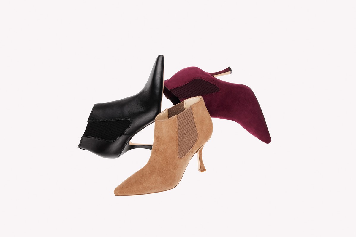 Three ankle boots in black leather, tan suede, and burgundy suede are set against a plain white studio backdrop, showcasing fall footwear.