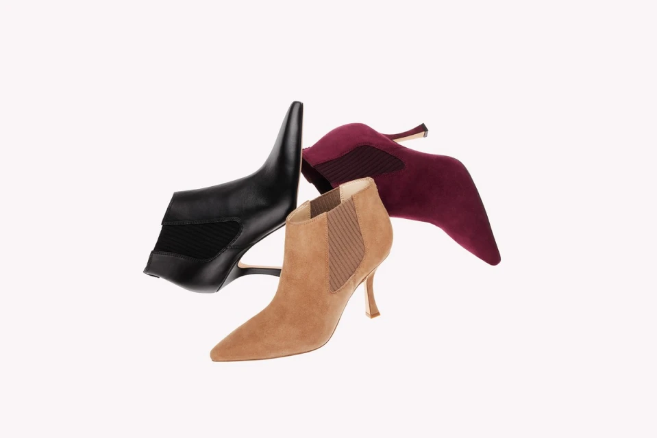 Three ankle boots in black leather, tan suede, and burgundy suede are set against a plain white studio backdrop, showcasing fall footwear.