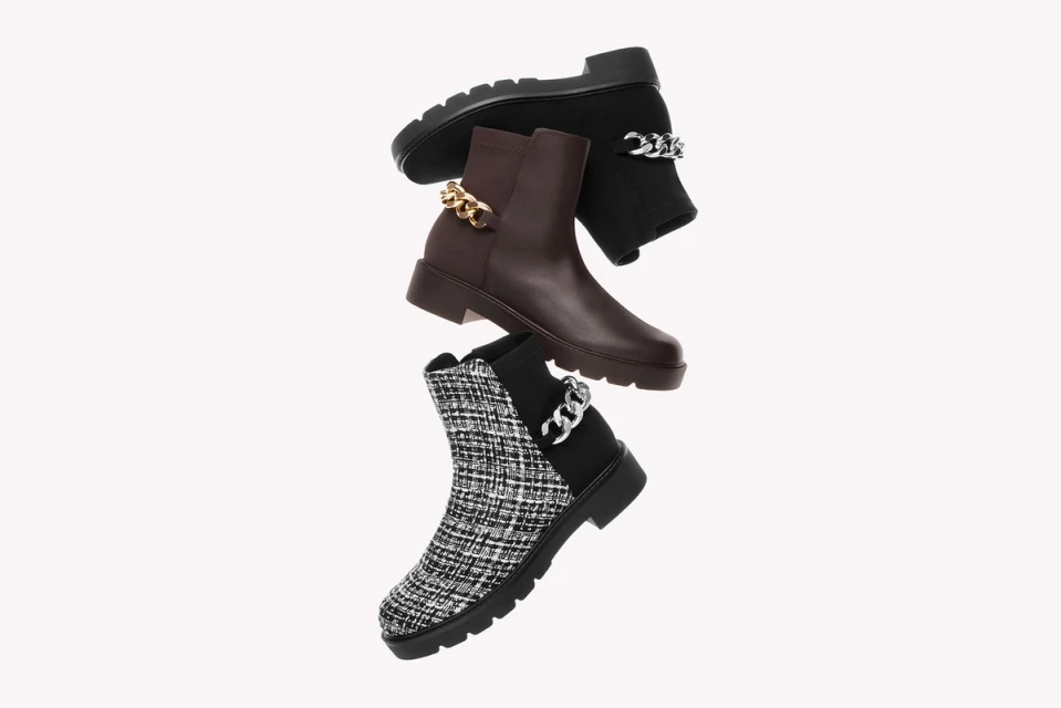 Three fashionable ankle boots are stacked against a white backdrop, each with distinctive textures, brown and black tones, and chain embellishments.