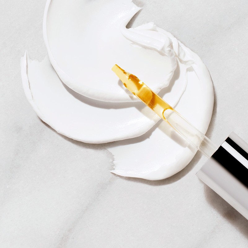 Close-up of white cosmetic cream with serum dropper applicator on marble background. Ideal for beauty and skincare advertising.