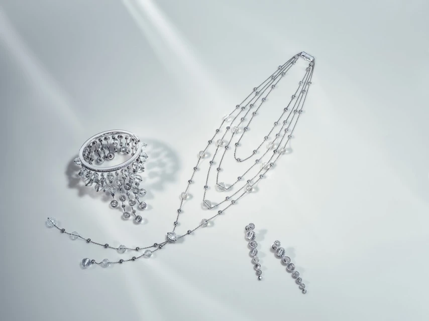 Elegant jewelry set featuring a bracelet, necklace, and earrings with clear gemstones on a clean white surface with diffused lighting.