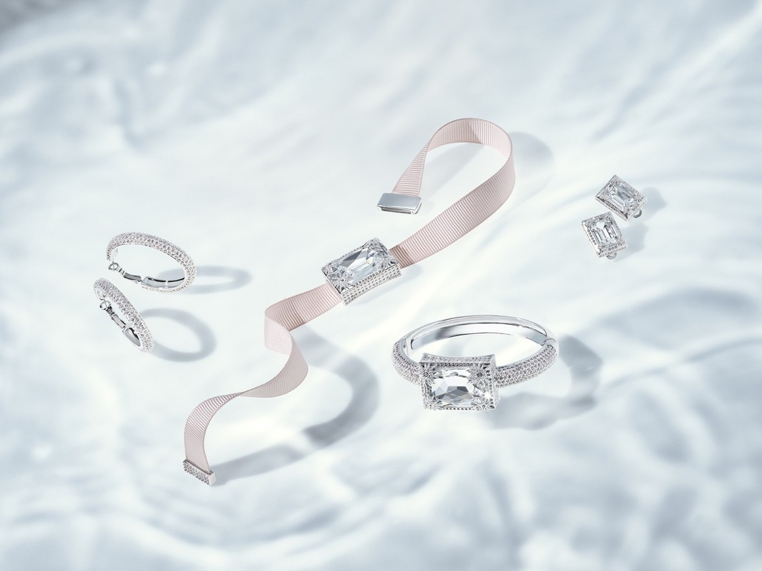 Elegant jewellery set featuring a bracelet, ring, and earrings with large, clear gemstones on a light, rippled background.